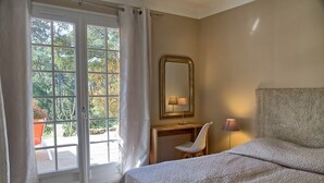 Un dormitorio con una cama, un escritorio, una silla, un espejo y una ventana con cortinas.