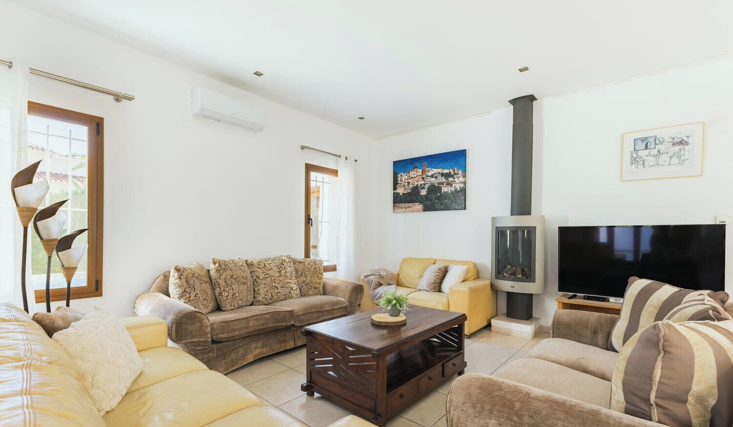 A living room with sofas, a coffee table, a fireplace, a TV, and a painting on the wall.