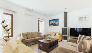 Una sala de estar con sofás, una mesa de centro, una chimenea, un televisor y un cuadro en la pared.