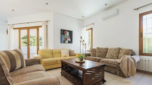 Een ruime woonkamer met een gele bank, een bruine bank en een houten salontafel.