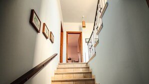 Un escalier avec une rampe en bois, des marches de couleur beige et une porte en bois en haut, qui donne sur une autre pièce.