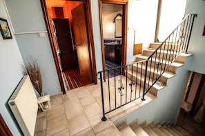 Staircase leads to an upper floor, flanked by light blue walls and a tiled floor.