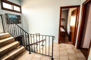 Staircase leads to a cozy landing with a door and bedside table.