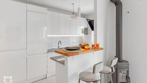 Una cocina moderna con armarios blancos, encimera de madera, estufa empotrada y una zona de bar con dos sillas.
