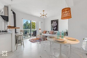 A modern kitchen with a gas stove, a dining area with a round table, and a living space with a sofa and a large window. - Villa SEAGULL by Abahana Villas (Calpe)