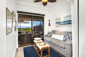 Ein Wohnzimmer mit grauem Sofa, einem Holztisch und Blick auf einen Balkon.