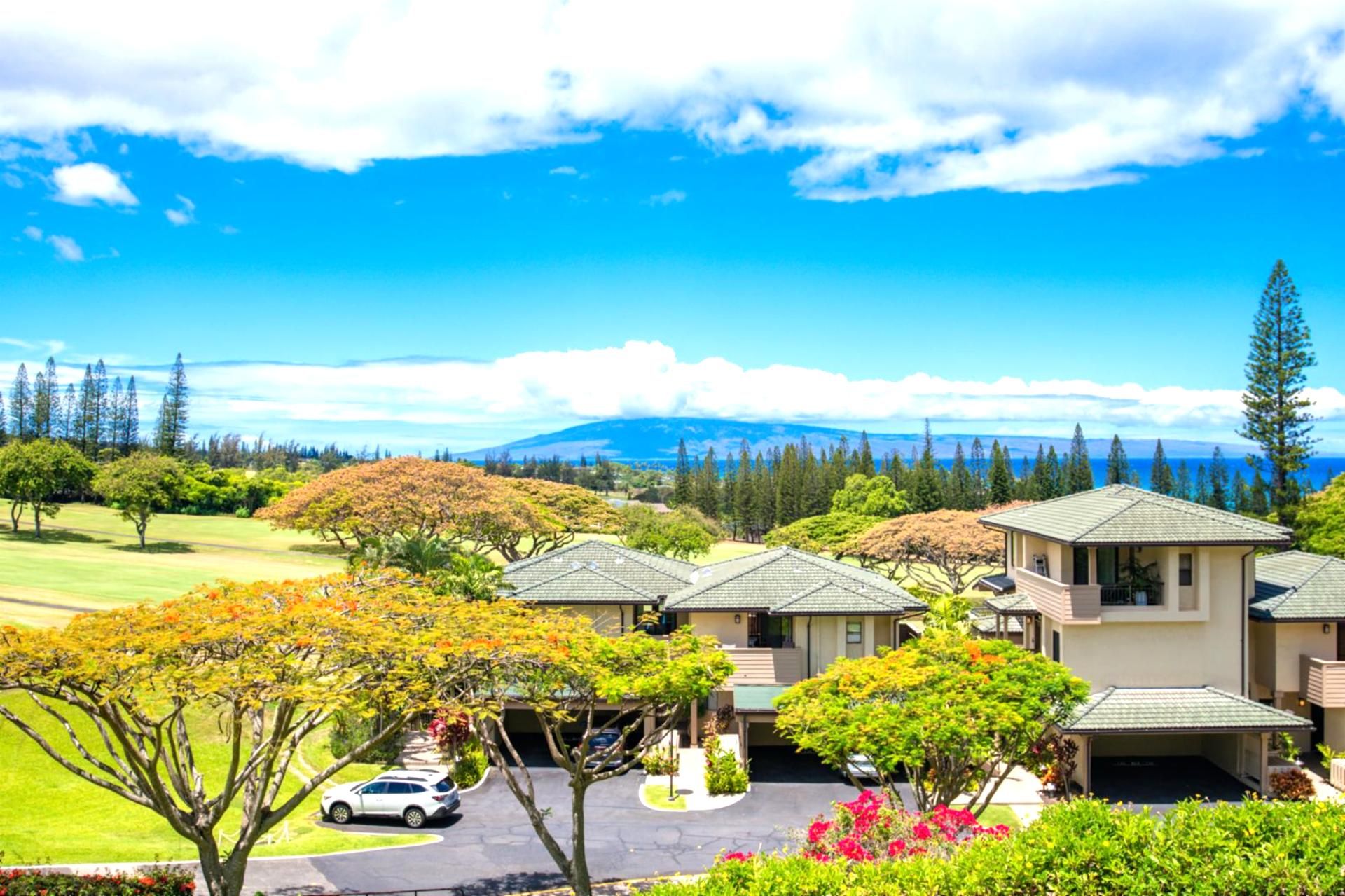 A residential area with multiple houses, a golf course, and a mountainous backdrop.