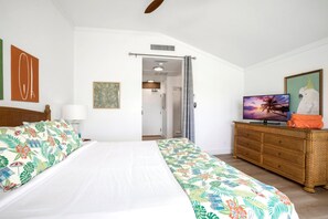Ein Schlafzimmer mit einem Bett, einem Fernseher, einer Kommode und einer Tür zu einem Badezimmer.