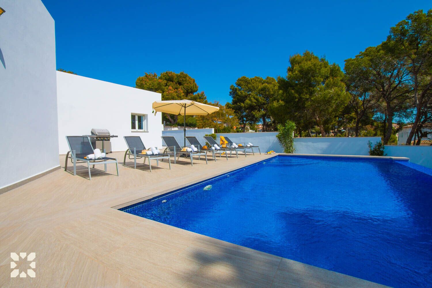 Une piscine avec des chaises longues et un espace barbecue.