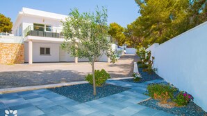 Un bâtiment moderne à la façade blanche, avec un petit arbre au premier plan et un chemin de gravier menant à l’entrée.