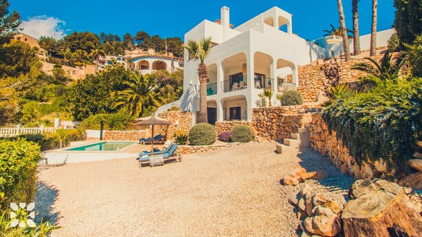 Eine große weiße Villa mit Swimmingpool, mehreren Balkonen und einer Steintreppe.