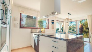 Eine moderne Küche mit einer großen Kochinsel, eingebautem Backofen und Geschirrspüler.