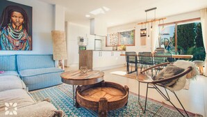 Ein modernes Wohnzimmer mit einer Couch, einem runden Holztisch und einem Essbereich mit Stühlen.
