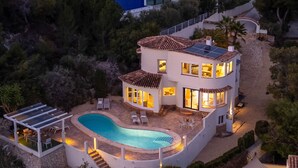 A two-story house with a swimming pool, outdoor seating, and solar panels.