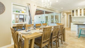 A dining area with a wooden table set for six, surrounded by chairs. - Sea Whisper: North End gem w/ pool & dock (Anna Maria)