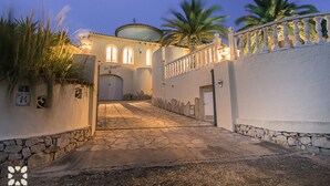 A paved pathway leading to a building with a dome and arched windows, flanked by stone walls and palm trees. - Villa MARIPOSA by Abahana Villas (Benissa)