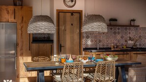 A kitchen with a wooden door, two hanging light fixtures, a tiled backsplash, and a dining table with wicker chairs. - Villa MARIPOSA by Abahana Villas (Benissa)