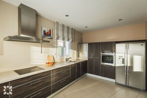 Een moderne keuken met een roestvrijstalen afzuigkap, een inbouwoven, een koelkast en een raam met uitzicht.