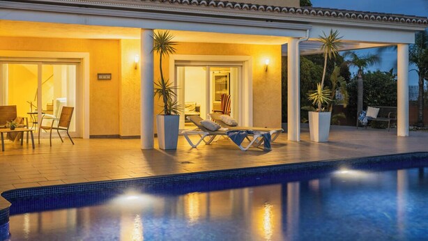 Uma casa moderna com piscina, área de estar externa e plantas em vasos.