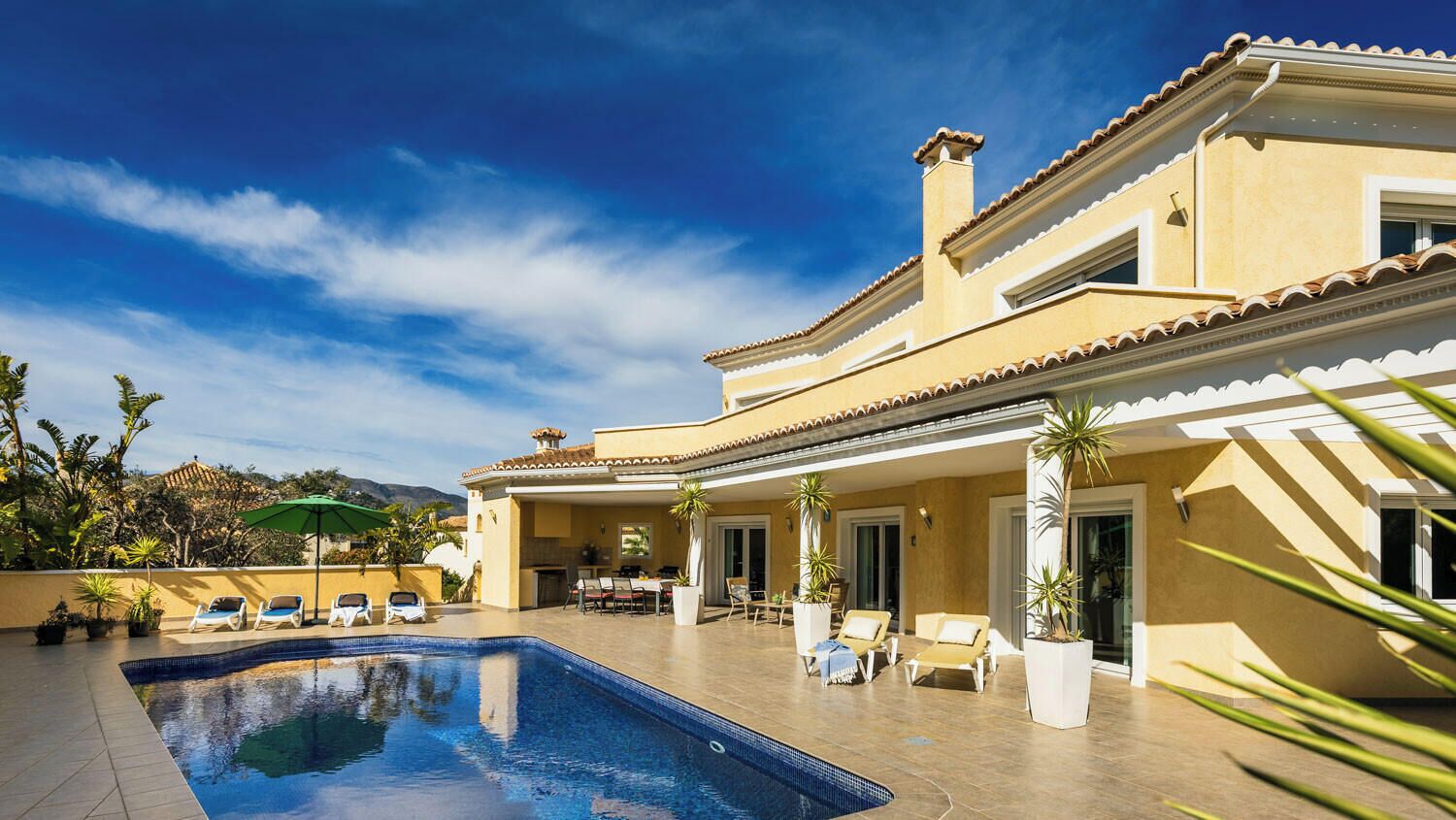 Un espace aménagé au bord de la piscine, avec des chaises longues et un coin repas.