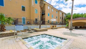 A spa pool area with a hot tub, lounge chairs, and a building with balconies in the background. - South Beach Rental!!  212 Brass Rail Condo (tybee island)