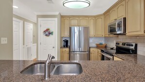 A kitchen with granite countertops, stainless steel appliances, and beige cabinetry. - South Beach Rental!!  212 Brass Rail Condo (tybee island)