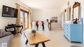 Una sala de estar con televisor, una mesa de madera, un sofá y un comedor con sillas.