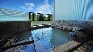 A hot spring area with stone walls, a metal fence, and a view of green hills. - Yusuge' Lake Haruna SPA Ryokan (Takasaki)