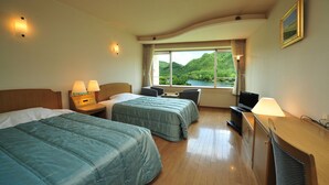 A hotel room with two beds, a desk, a TV, and a window with a view of greenery. - Yusuge' Lake Haruna SPA Ryokan (Takasaki)