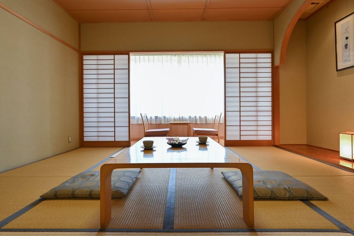 A traditional Japanese room with tatami flooring, a low table with a bowl and chopsticks, and shoji screens.