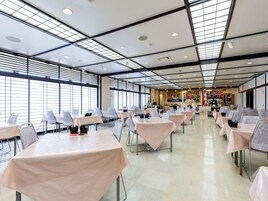 Un comedor amplio con mesas y sillas, ventanas grandes y un alto techo con tragaluces.