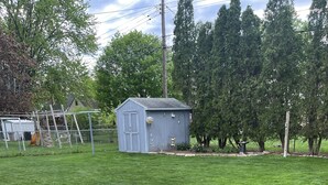 A well-maintained backyard with a stone fire pit, a small shed, and a fenced area. - In the shadows of Lambeau Field is our Packer House (Green Bay)