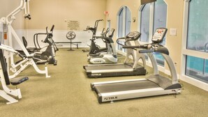 Un gimnasio con cintas de correr, elípticas y máquinas de pesas.