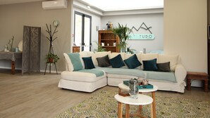 A modern living room with a sectional sofa, a coffee table, and a decorative wall with a geometric design. - A.ti.tudo Nature (Portimão)