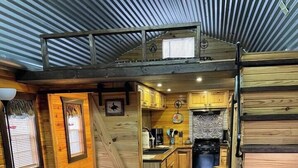 Ein gemütliches Blockhaus-Interieur mit einer Holztreppe, einem Ledersofa und einer Küchenzeile.