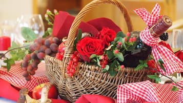 Una cesta de mimbre llena de rosas rojas, bayas rojas y una botella adornada con un lazo de cuadros.