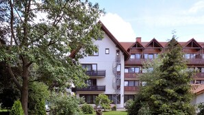 A multi-story building with balconies, a paved driveway, and well-maintained greenery. - Parkhotel zum Stern (Oberaula)
