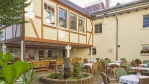 A traditional European-style building with a courtyard featuring outdoor seating and a central fountain. - Parkhotel zum Stern (Oberaula)
