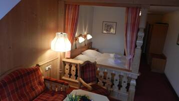 Ein gemütliches Zimmer mit einem Bett, einem Sofa und einem Tisch mit Pflanze und Obst.