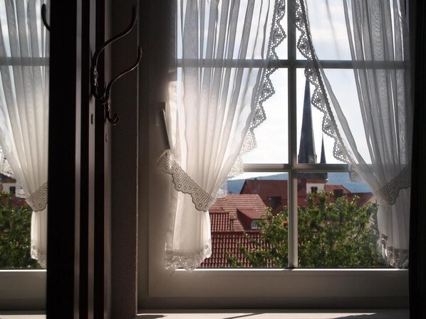 Una ventana con cortinas blancas y vista a un edificio de techos rojos.