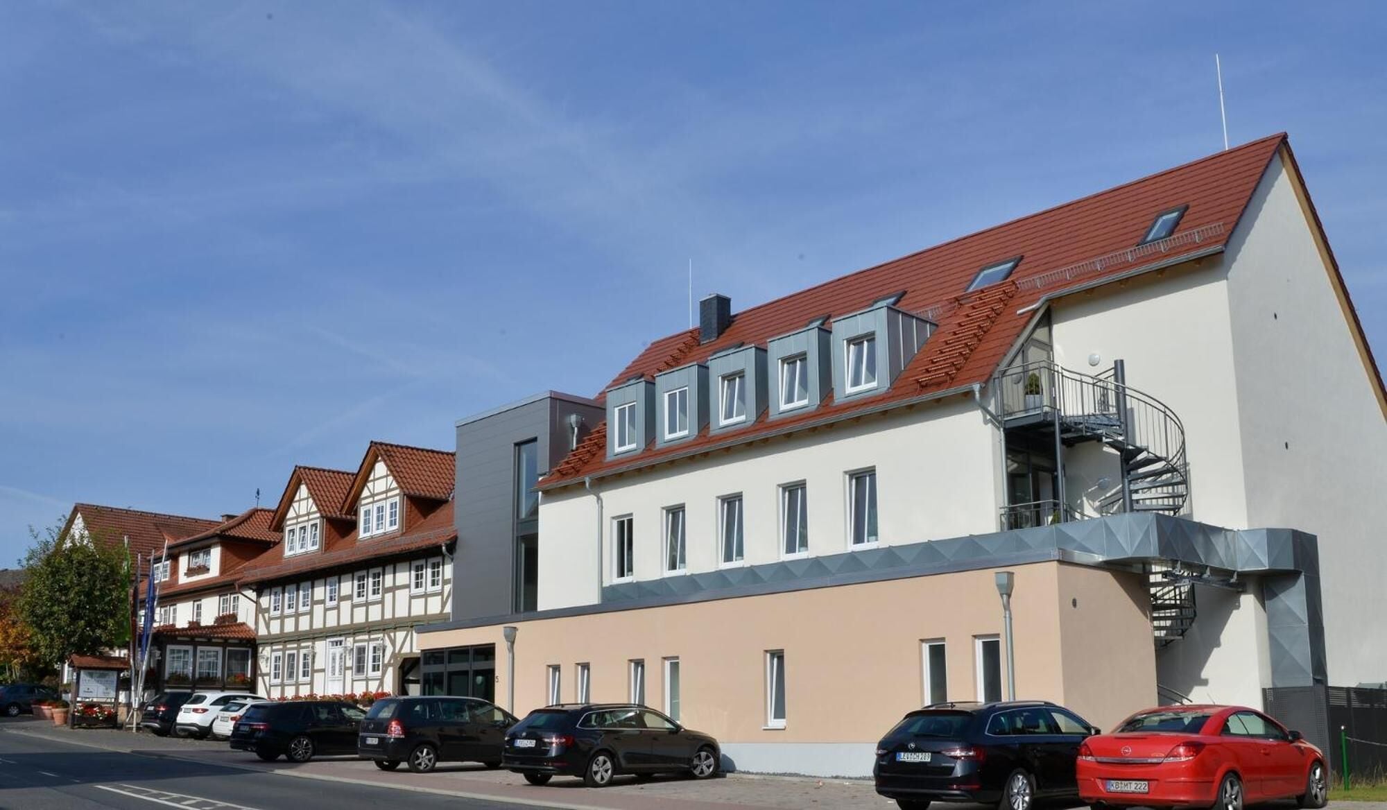 A modern building with a red roof, multiple windows, and a visible staircase.