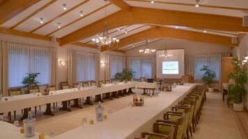 A conference room with a long table, chairs, and a projector screen.