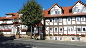 Ein traditionelles Fachwerkhäuschen mit rotem Ziegeldach, einem kleinen Laden im Erdgeschoss und Blumenkästen an der Fassade.