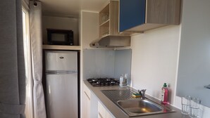 A compact kitchen with a refrigerator, microwave, stove, and sink. - mobile home 2018 with terrace (Argelès-sur-Mer)