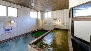 Un baño público con dos piscinas, paredes de azulejos y ventanas.