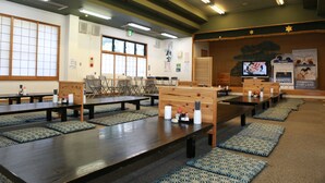 Un restaurante con mesas de madera largas, cojines estampados azules y una decoración tradicional japonesa.