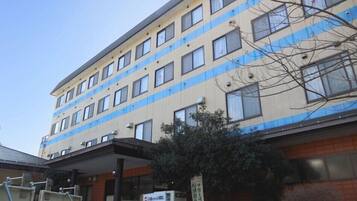 Hotel features a flat facade with a grid-patterned window design and a covered entrance.
