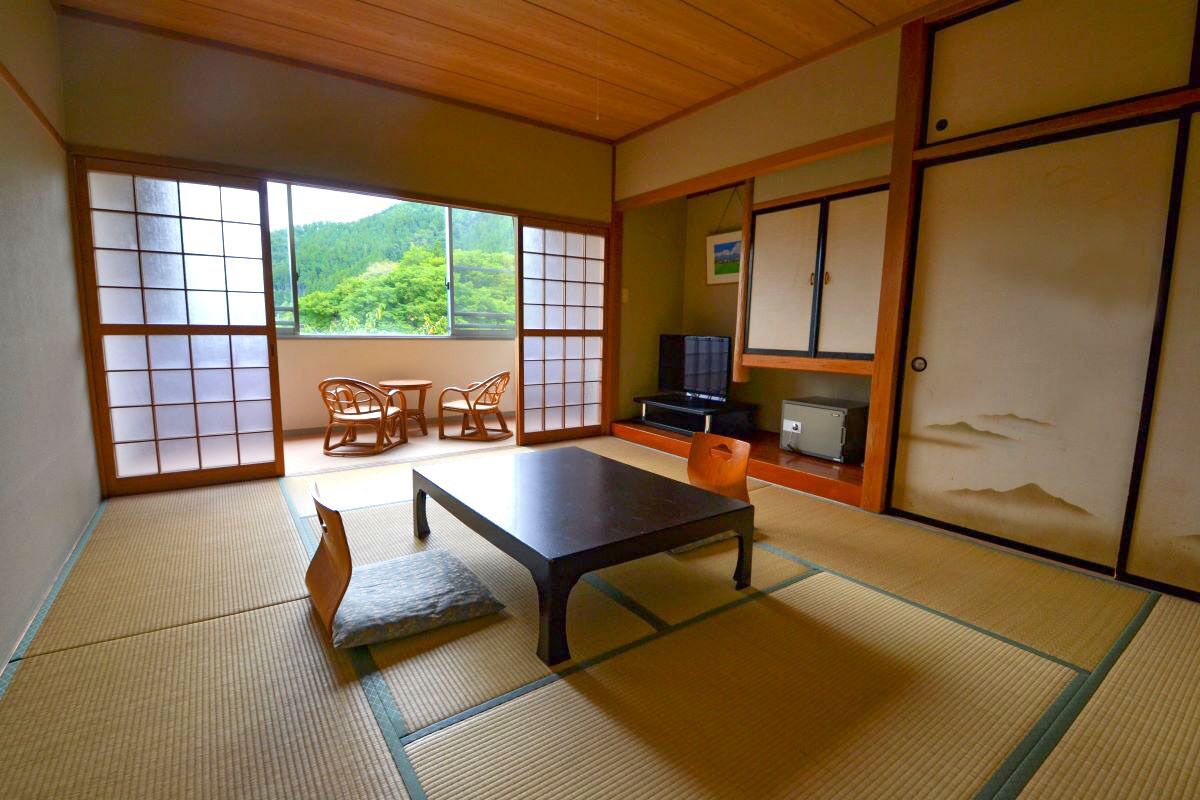A traditional Japanese room with tatami flooring, a low table, and sliding doors.