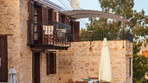 A stone building with a balcony, outdoor seating, and a satellite dish. - rosalia apartment    (Chalki)