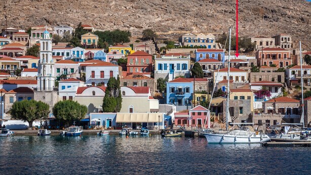 A coastal town with colorful buildings, a marina with boats, and a hill in the background. - rosalia apartment    (Chalki)